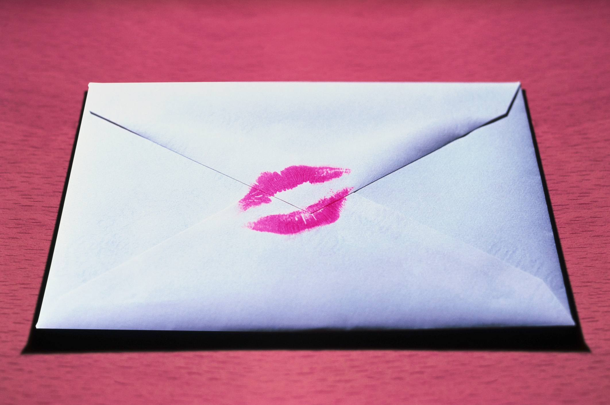 White envelope sealed with a pink lipstick kiss mark, symbolizing romance or a love letter