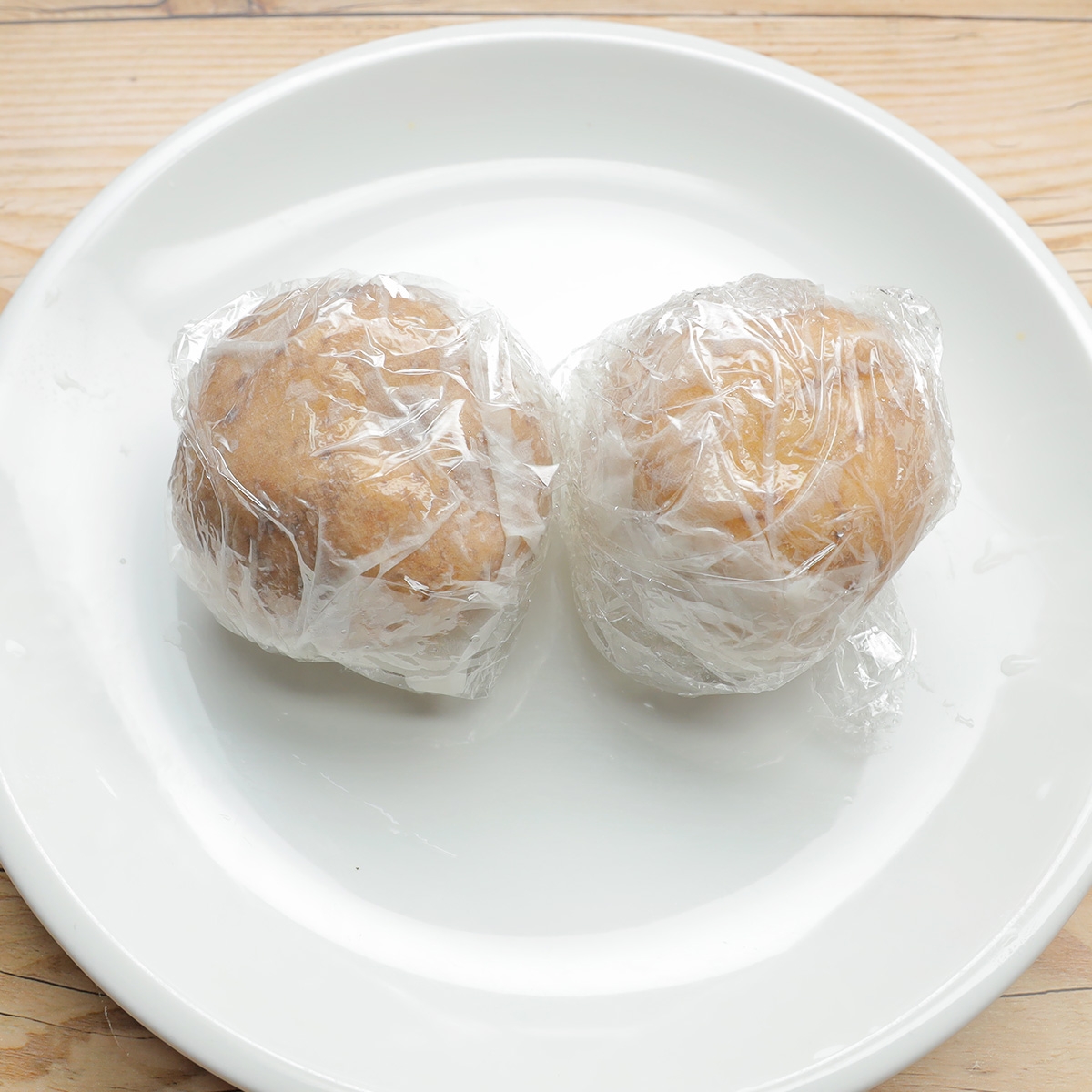 皿の上にラップで包まれた2つの芋