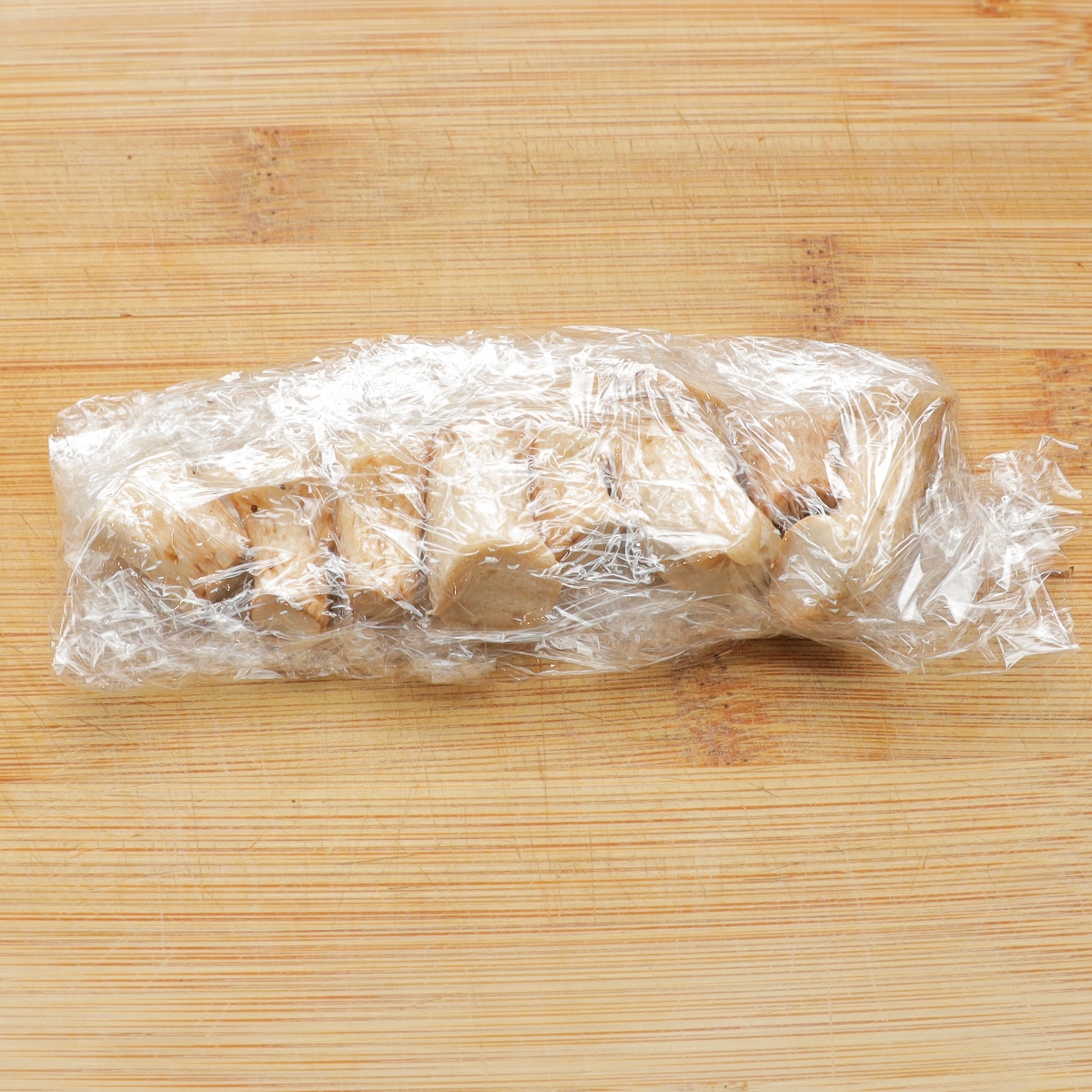 木製のまな板の上にラップで包まれたパンのスライス。