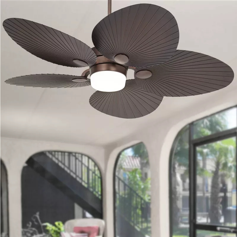 Ceiling fan with leaf-shaped blades in a modern, airy room with large windows and staircase
