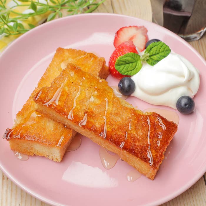 皿にパン、ホイップクリームとベリーが添えられた朝食。