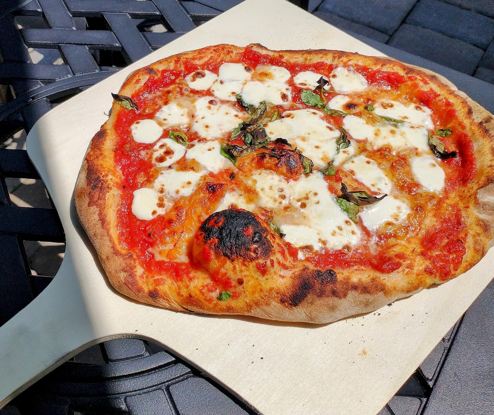 Pizza with melted food  and basil connected  a woody  peel, resting connected  a patio table. Perfect for outdoor eating  oregon  a summertime  look    feature
