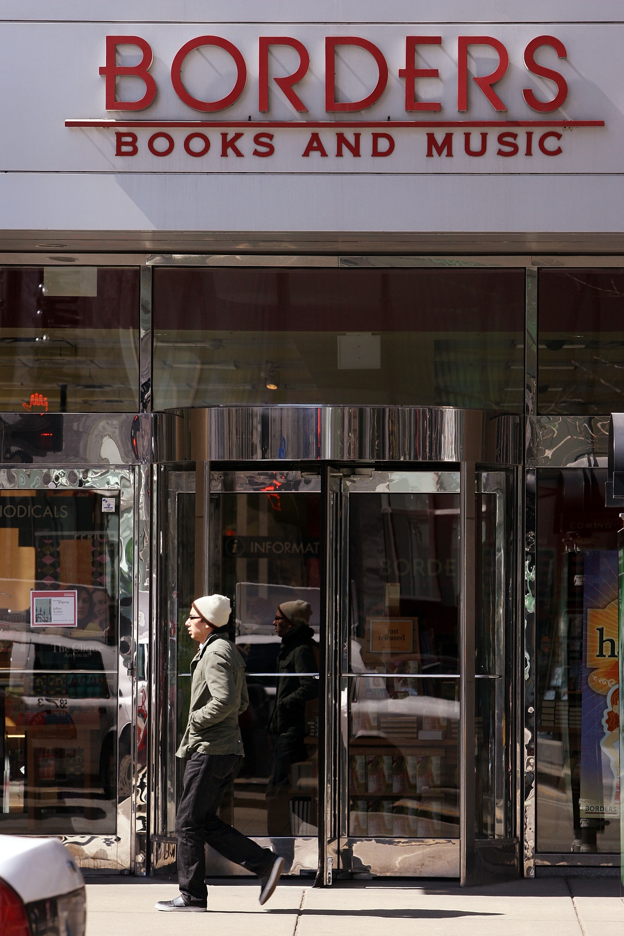 A person walks past a closed Borders bookstore with visible signage reading &quot;Books and Music.&quot;