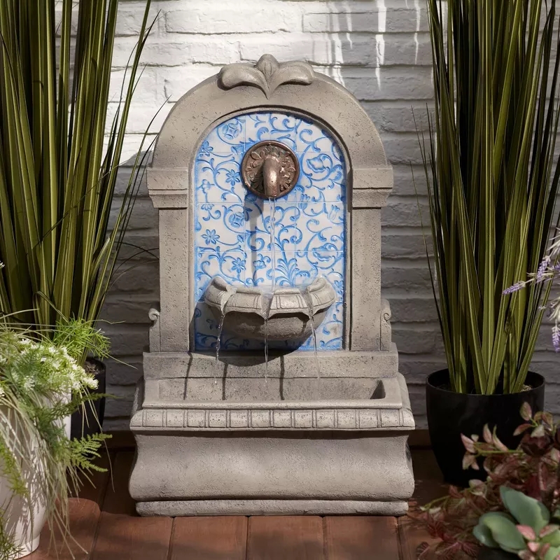 Wall-mounted garden fountain with floral tile design, surrounded by potted plants, is featured as a shopping item