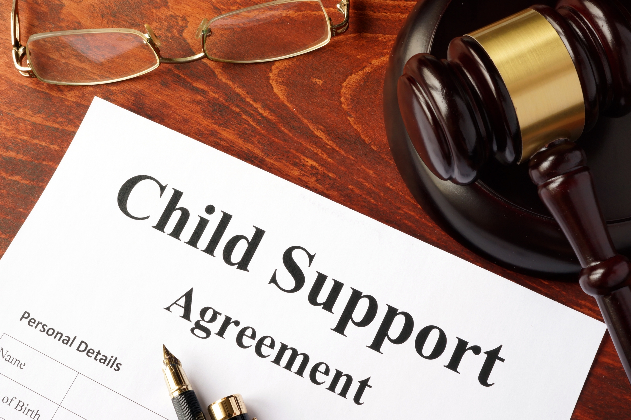 Child Support Agreement document with a pen, glasses, and gavel on a desk