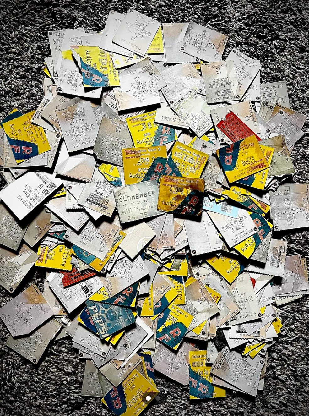 Scattered movie ticket stubs from various films are spread out on a textured surface