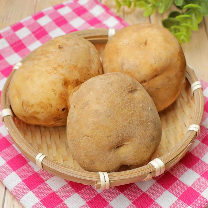籐のバスケットに入った3つのじゃがいも。テーブルクロスが下に敷かれている。