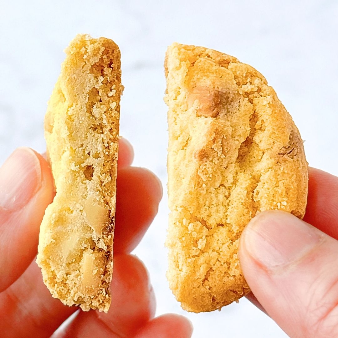 手で持たれた2つのクッキーのクローズアップ。松の実が見える。