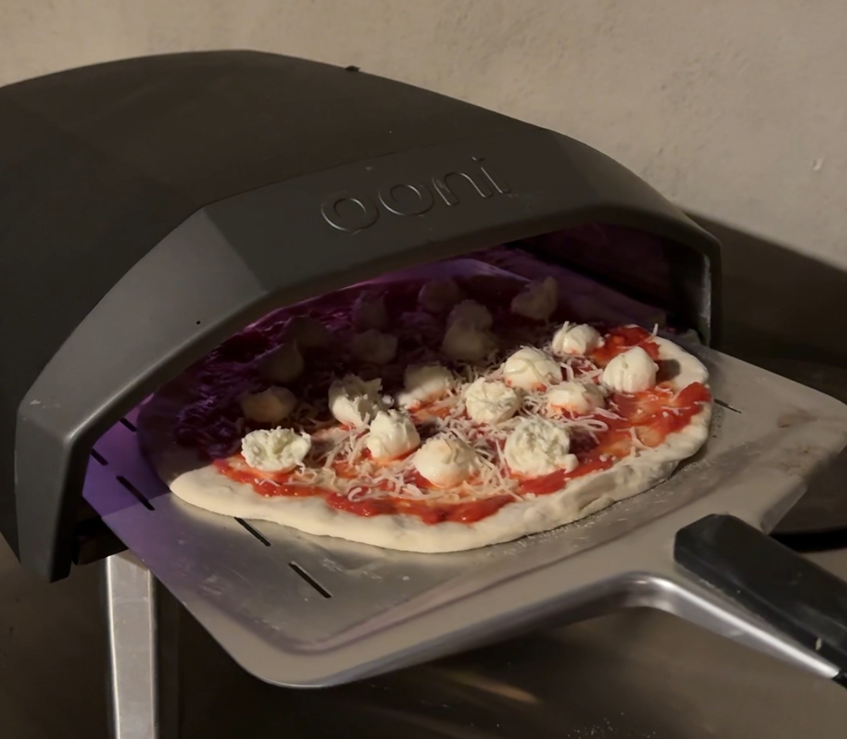 Pizza dough with toppings going into an oven