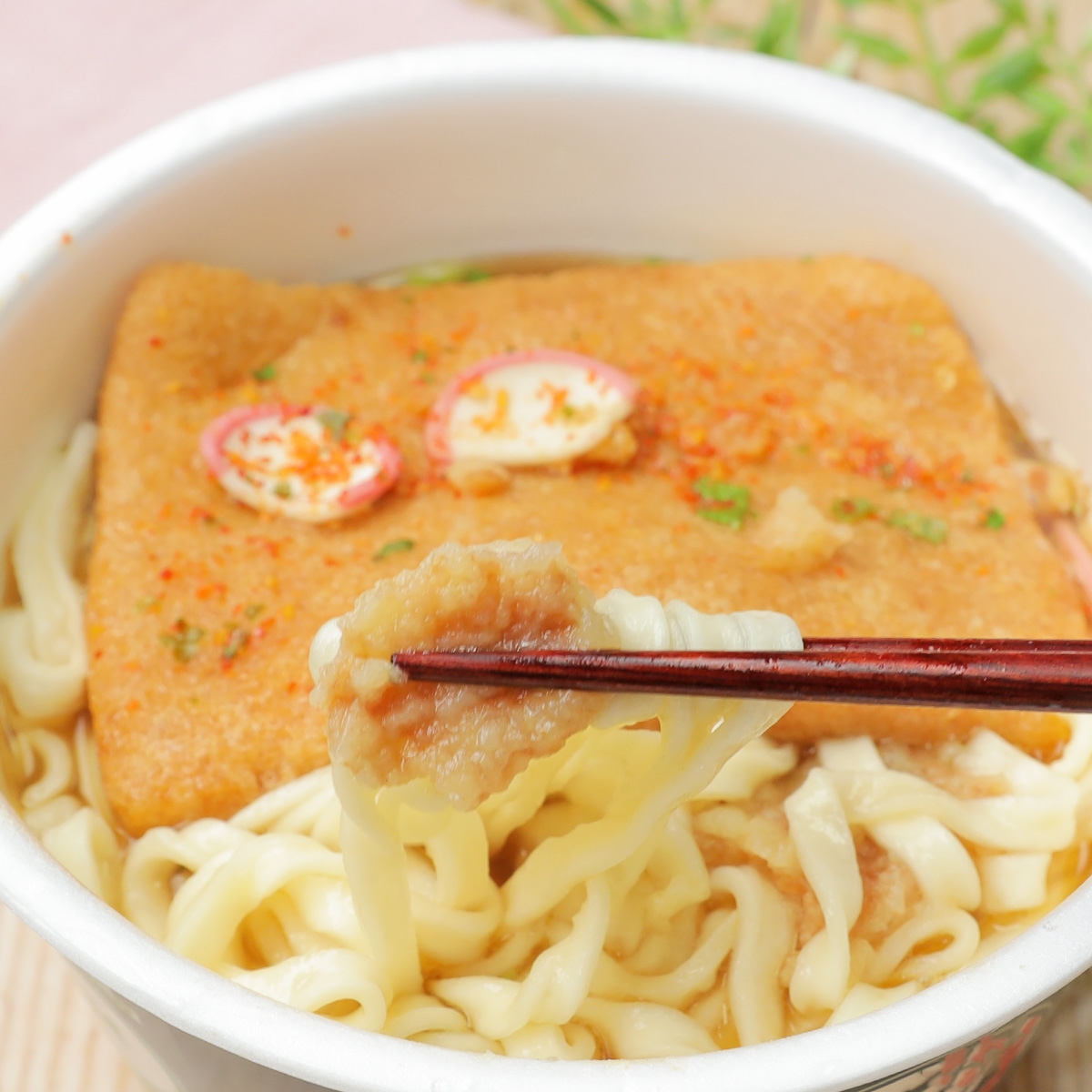 器に盛られたうどんと揚げ、箸で持ち上げられている様子。