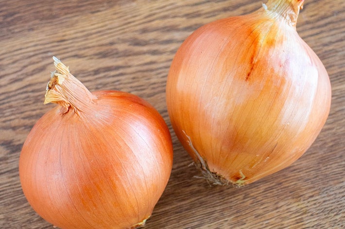 2つの玉ねぎが木のテーブルの上に置かれている。