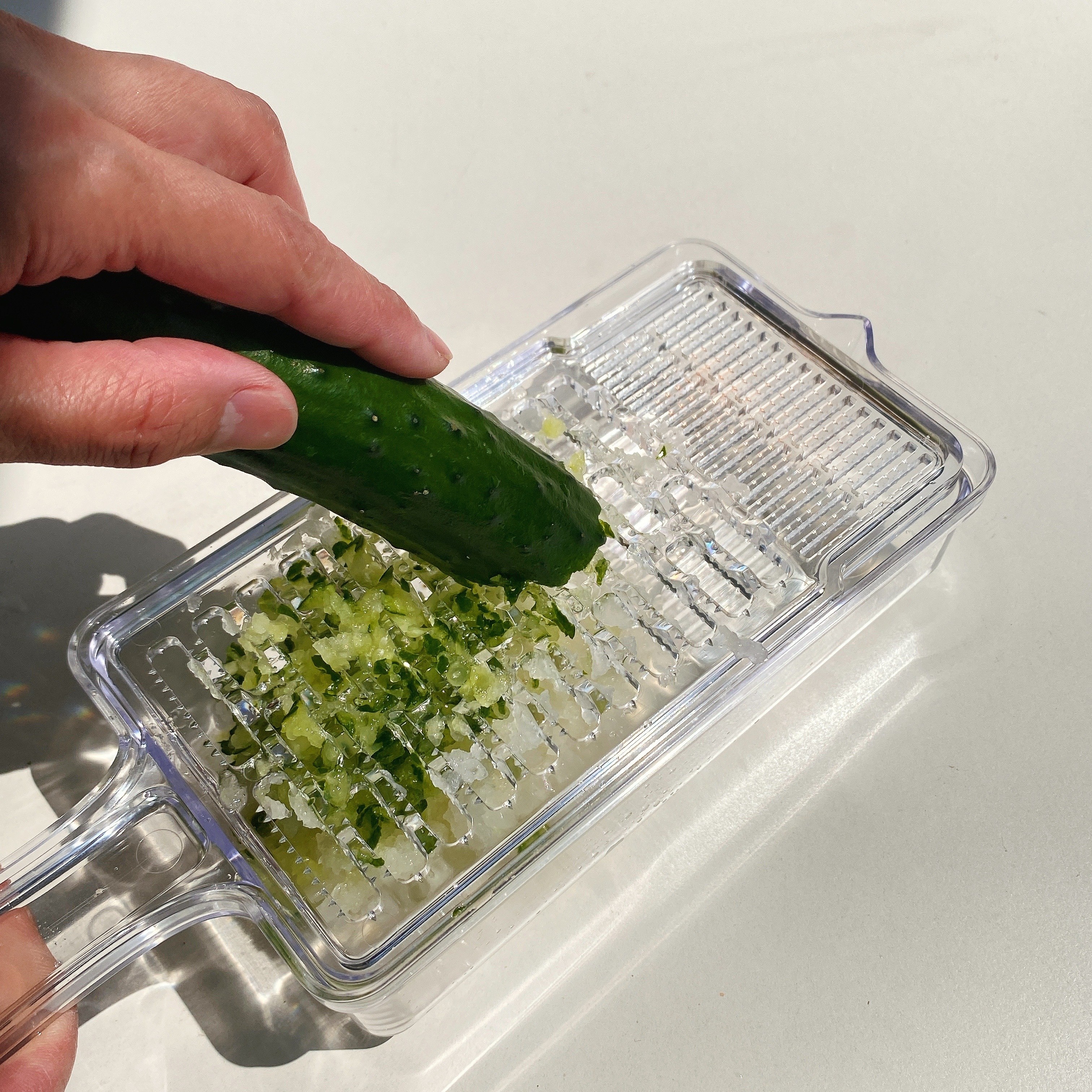 手でキュウリをおろし金ですりおろしている様子。