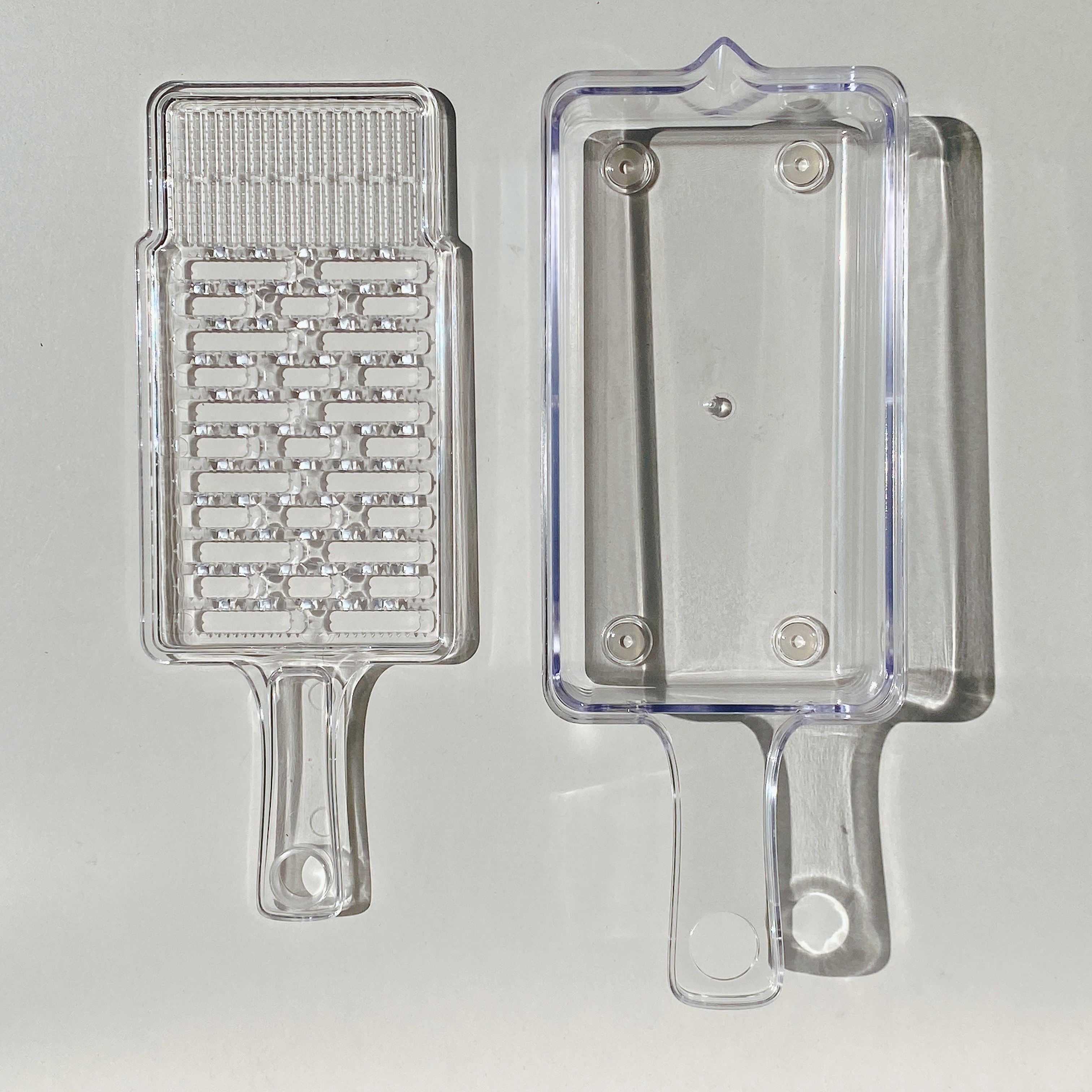 透明なプラスチックの調理用おろし器と受け皿。
