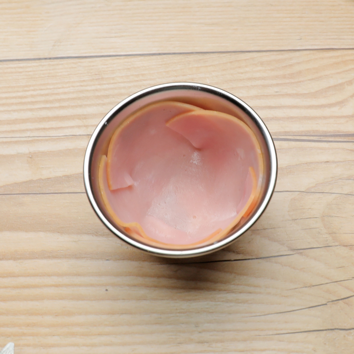 ハムが並んだ小さなボウル。木製テーブルの上に置かれている。