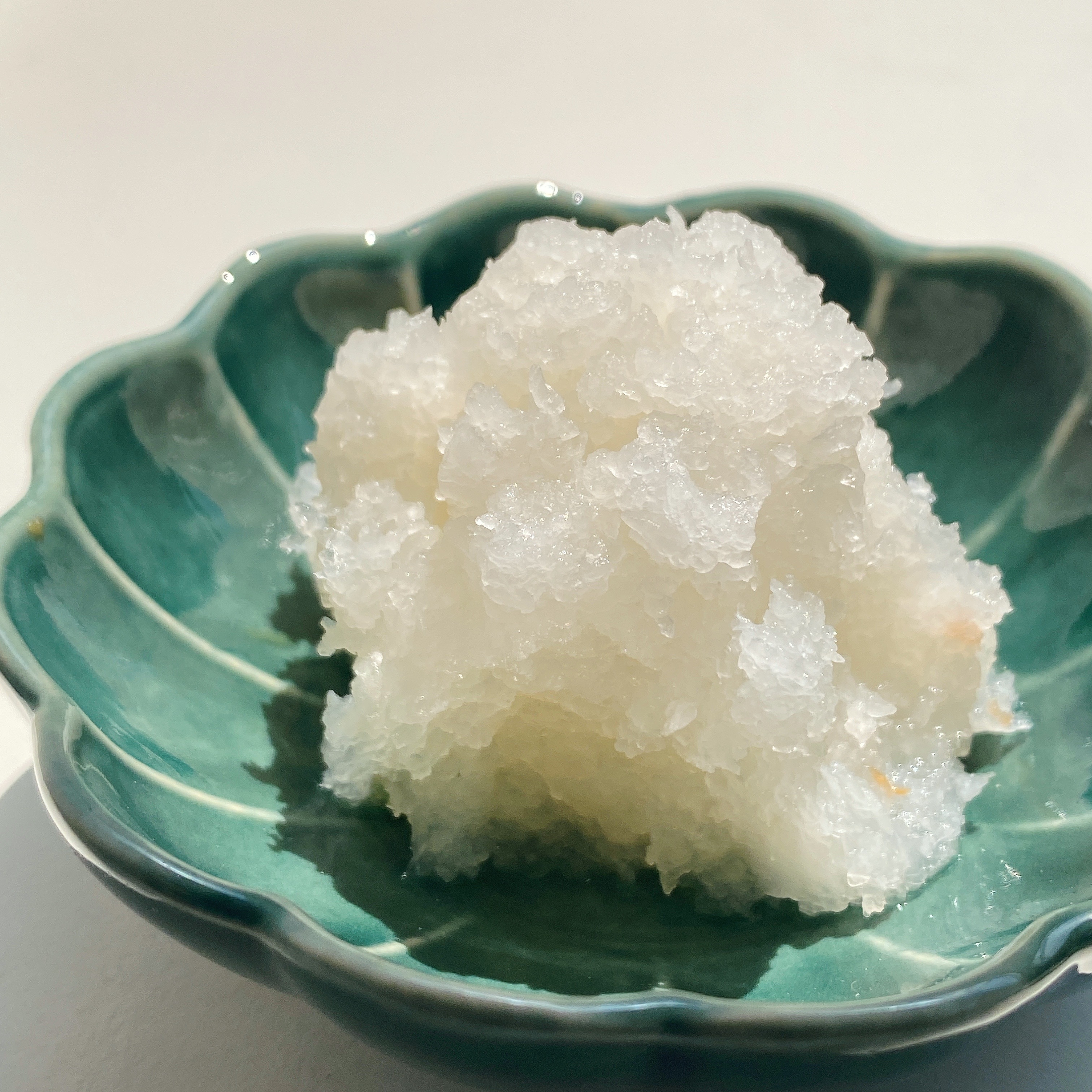 緑の小皿に盛られたおろし大根。テーブルの上に置かれている。