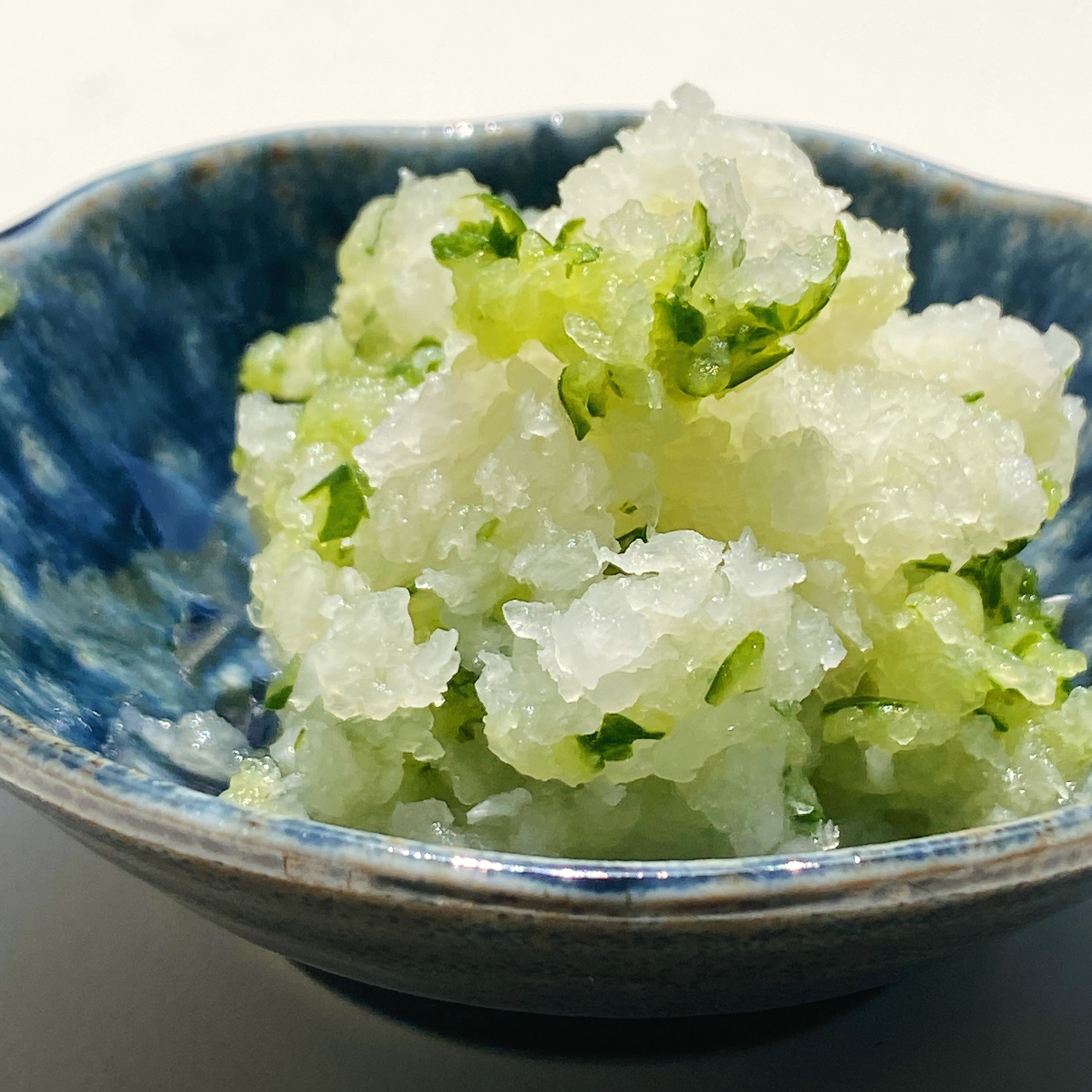 すりおろした大根と青じそが盛られた青い器に入っているディッシュ。