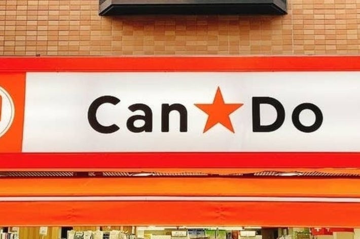 100円ショップ「Can★Do」の看板。レンガ調の背景に白地に黒文字、赤い星が中央に配置されている。