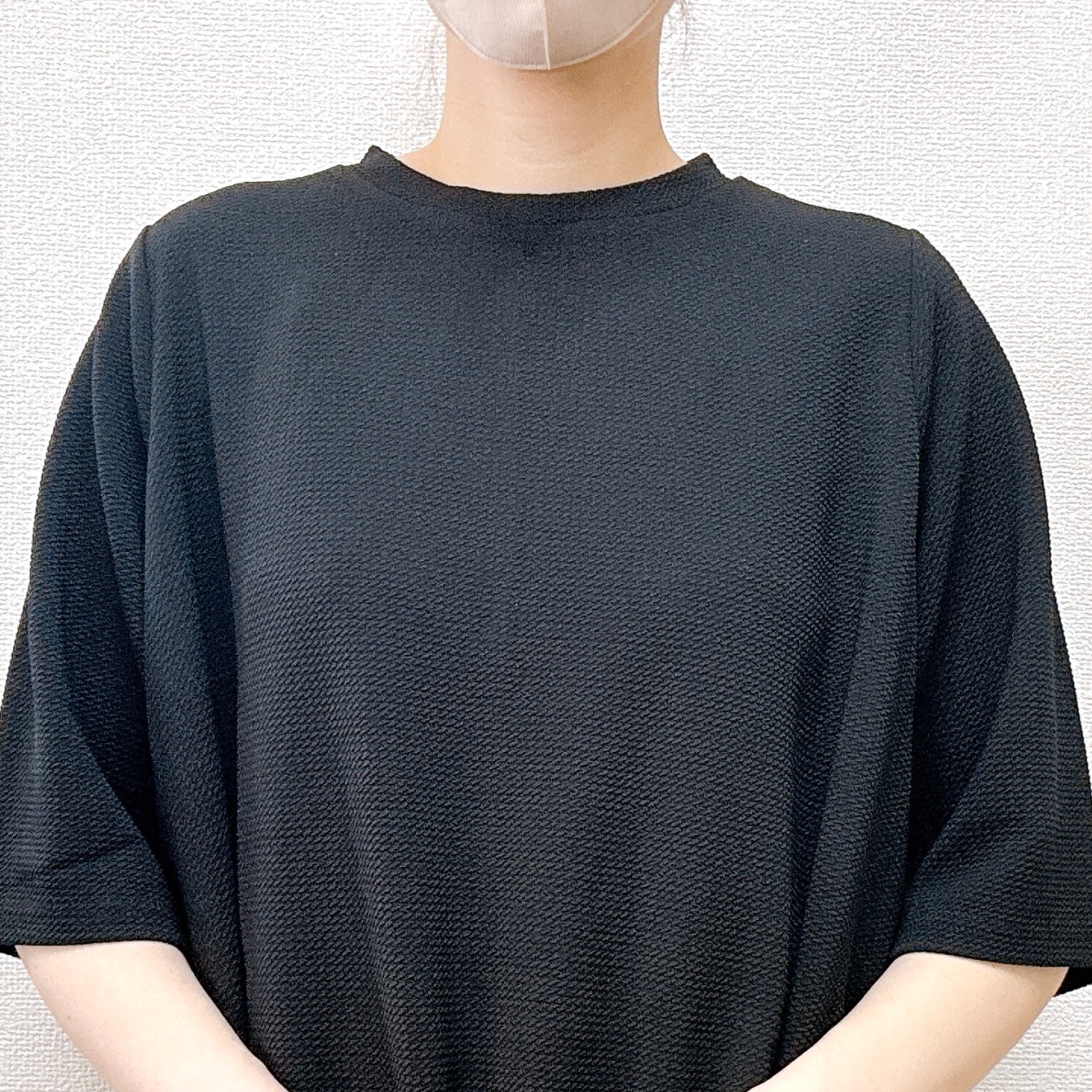女性が黒いカジュアルなシャツとフェイスマスクを着用している姿。