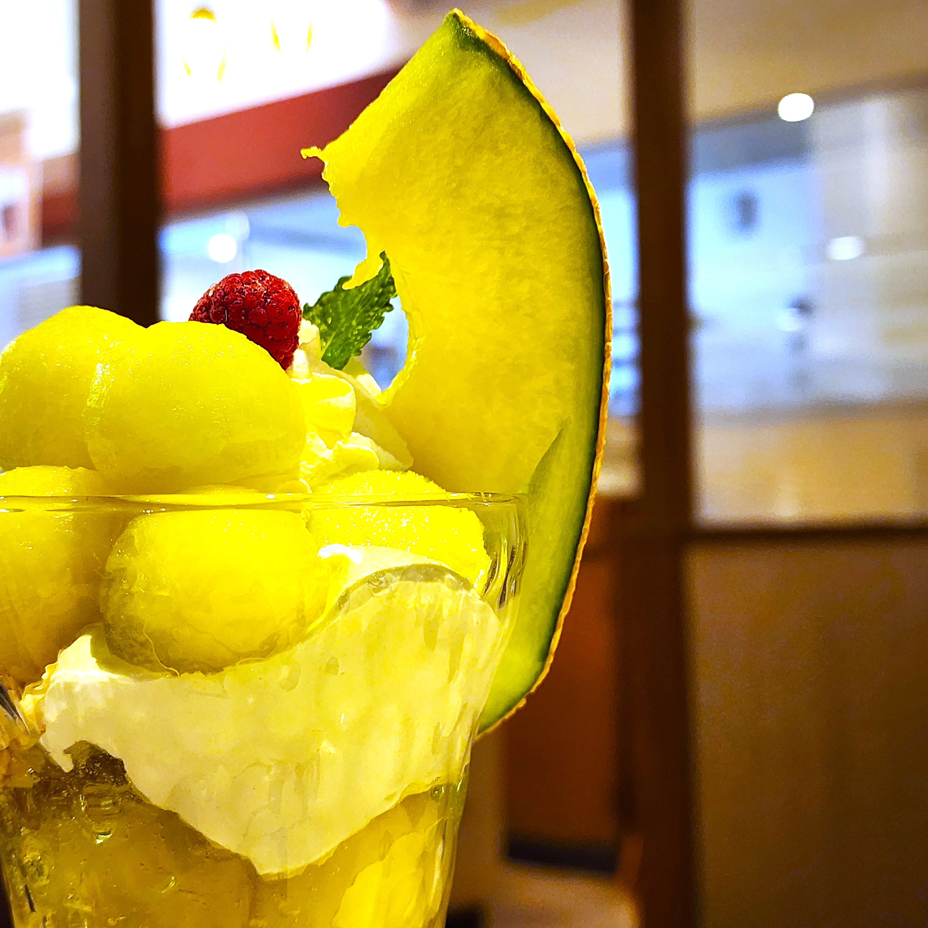 メロンとクリームが飾られたデザートパフェ。鮮やかな果実がトッピングされ、涼しげな見た目。