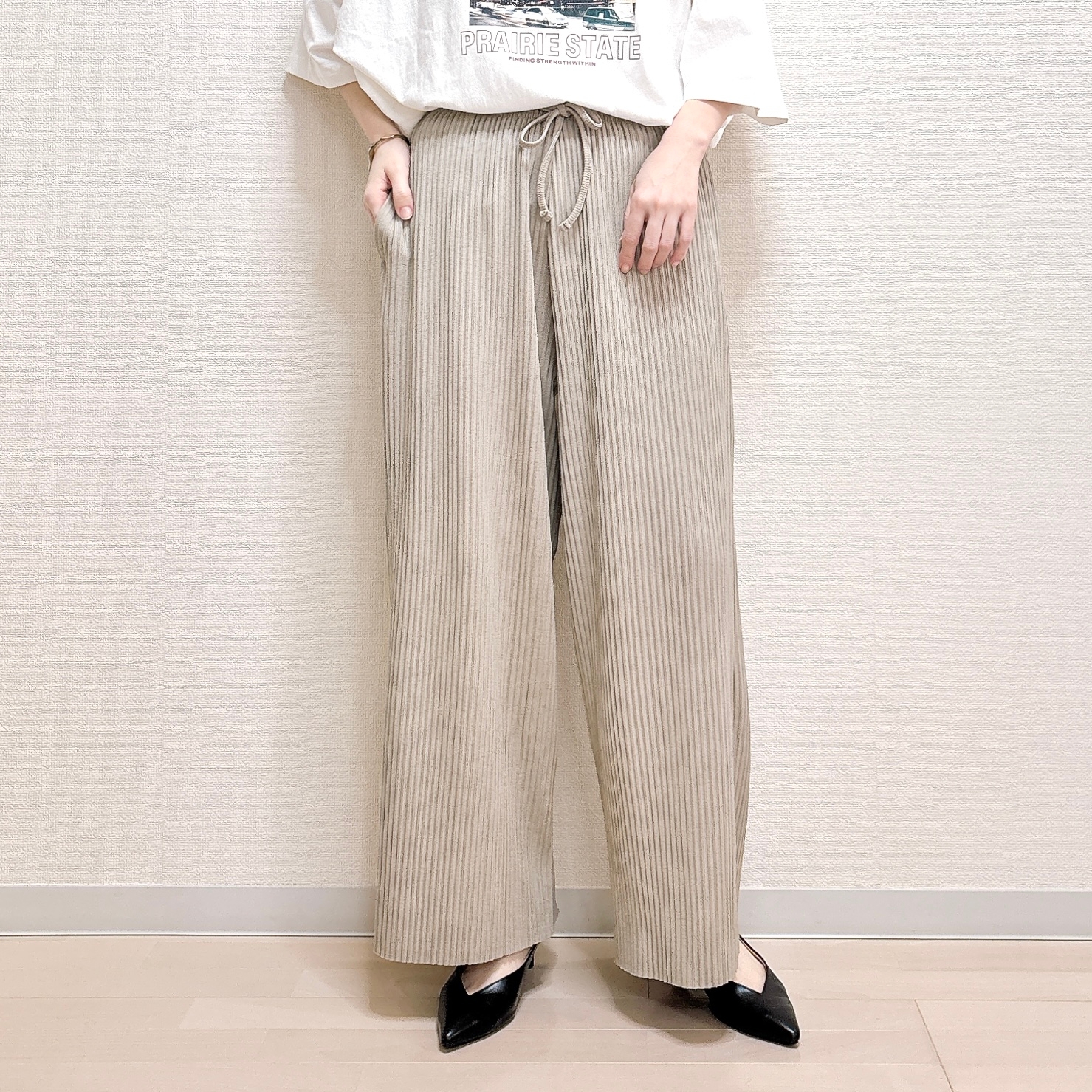 人物がカジュアルなTシャツとワイドパンツを着用し、リラックスしたスタイルを見せている。