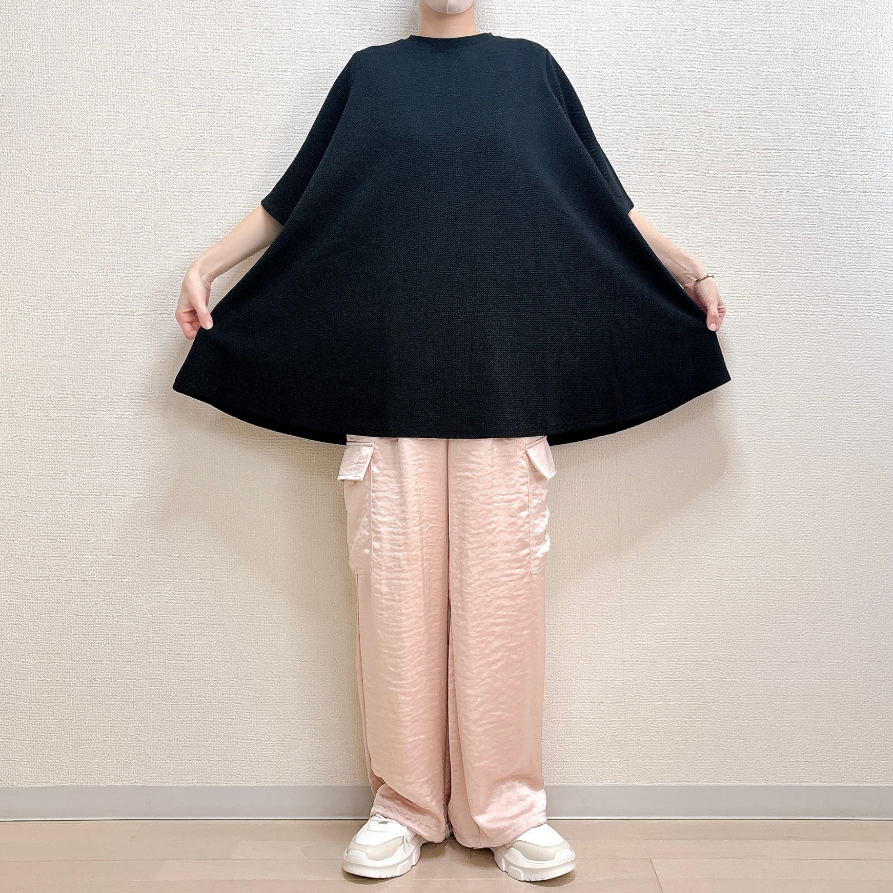 人がゆったりしたトップスとカーゴパンツを着てポーズを取っています。