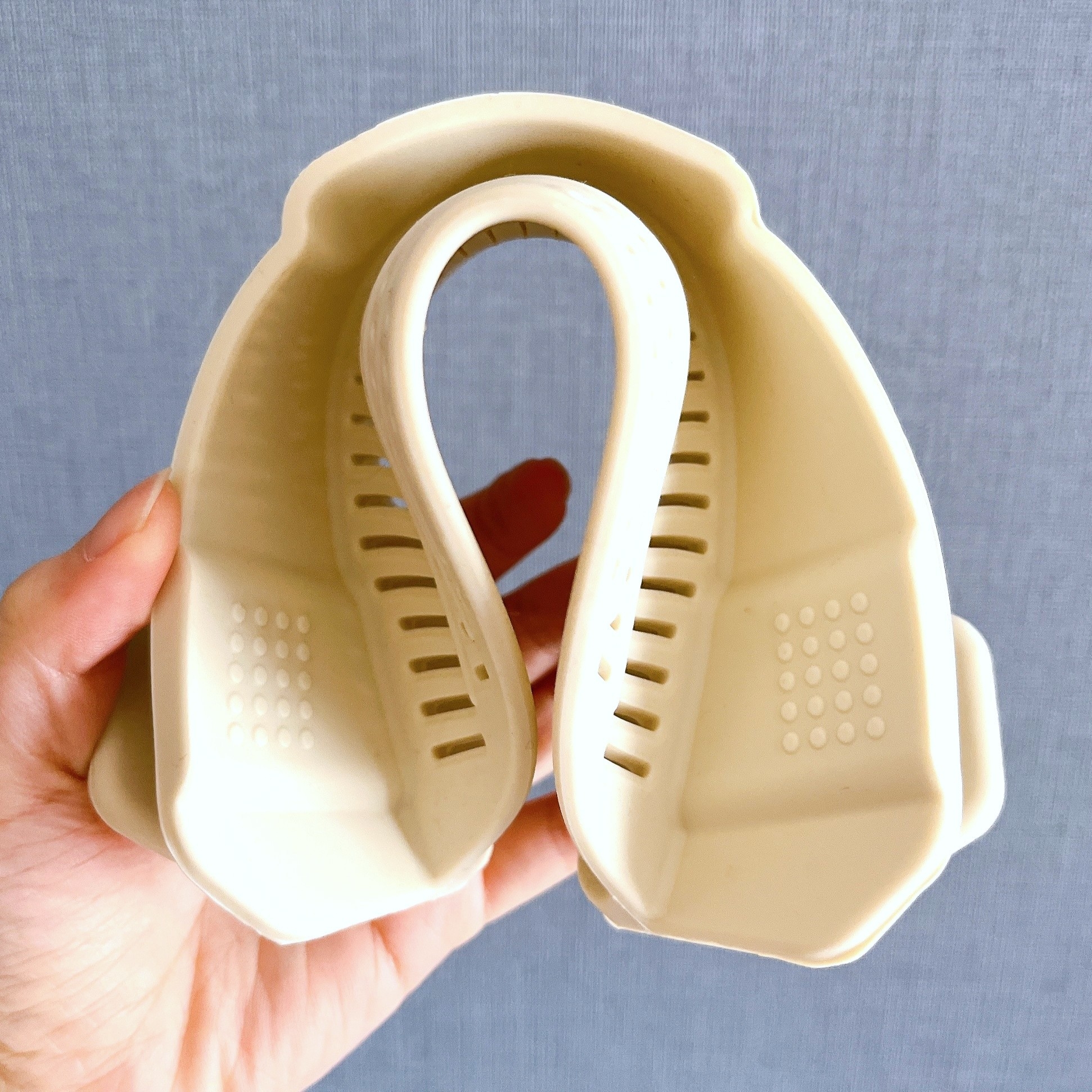 手に持たれた二つ折りのシリコン製レンジ用パスタストレーナー。