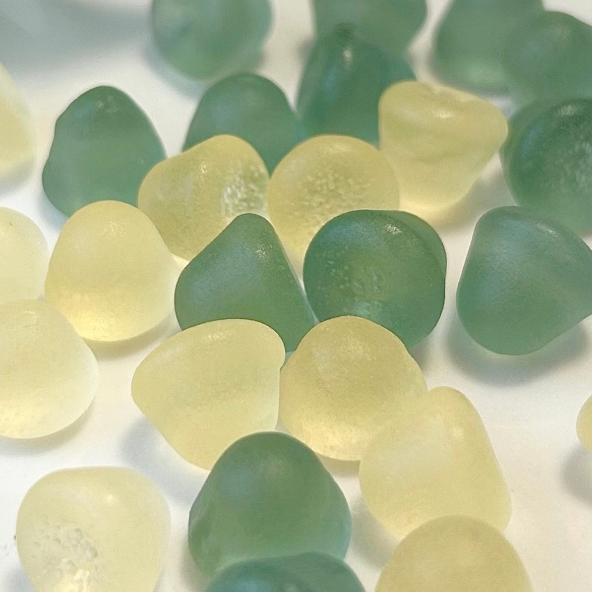 砂糖をまぶした緑色と薄黄色のグミが平らな面に広がっています。