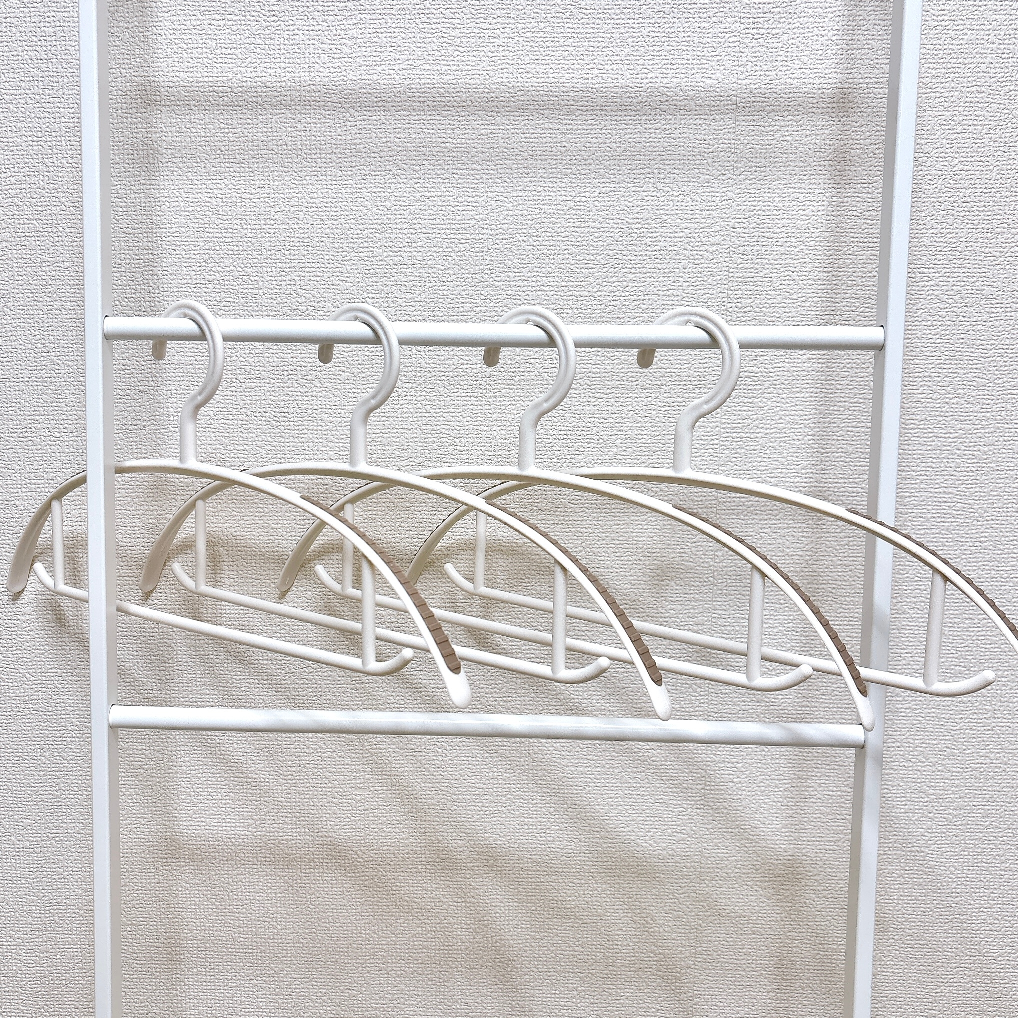 4本の洋服ハンガーがバーに掛けられているシンプルな画像。