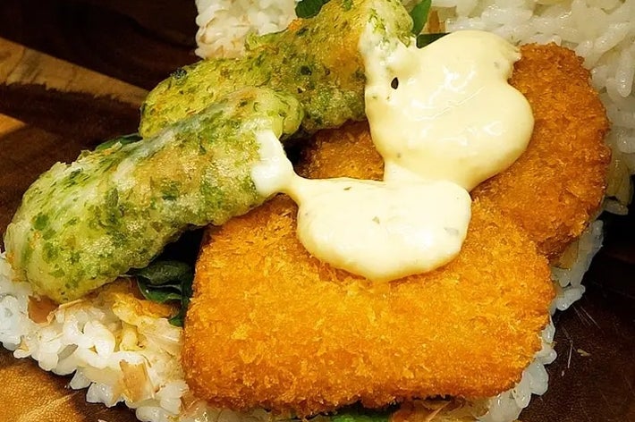 ご飯の上にフライとソース、緑のトッピングをのせたサンドイッチ。