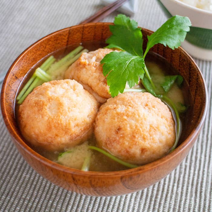 木製の器に盛り付けられたスープには、大きな練り物と野菜が浮かんでいます。