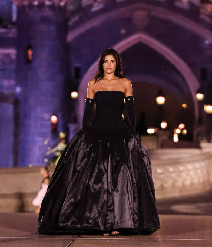 Kylie Jenner in a dramatic black evening gown in front of a castle backdrop at night