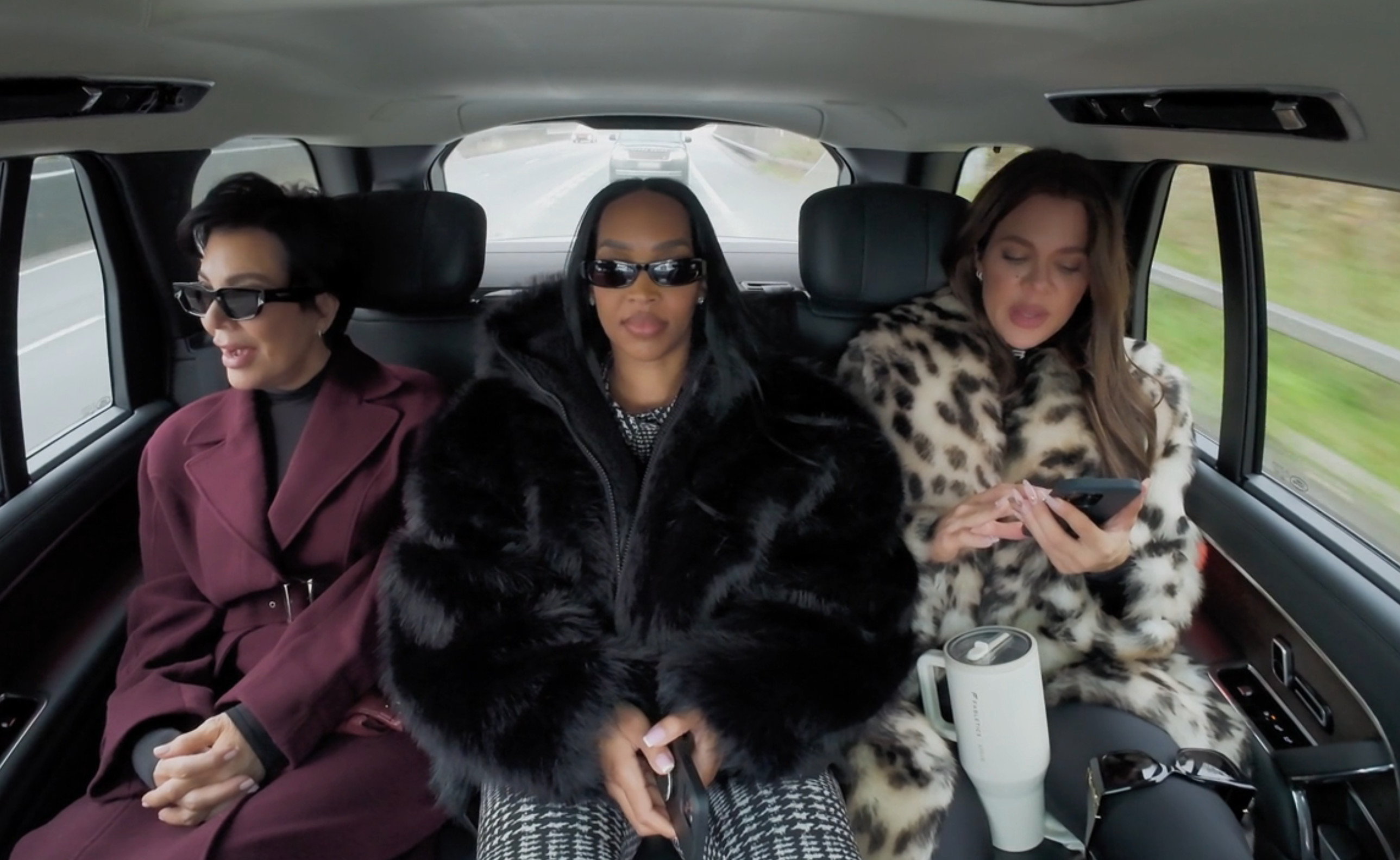 Kris Jenner, Malika Haqq, and Khloé Kardashian chatting in the back of a car, with Khloé reading something from a phone