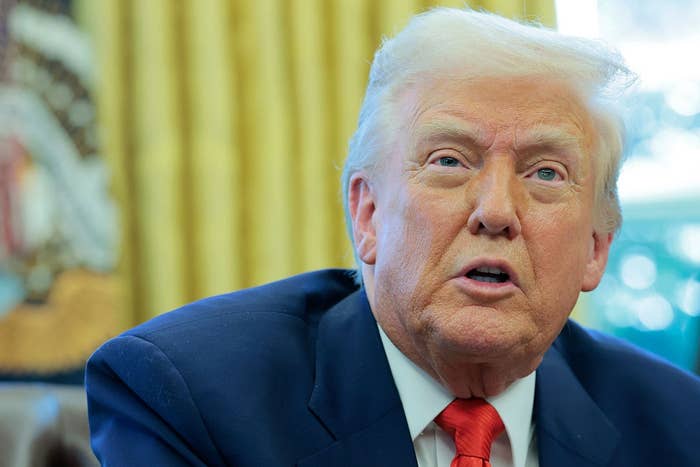 I don’t know who this is, but the image shows a person in a suit and tie speaking, possibly in an official setting, with a backdrop of curtains