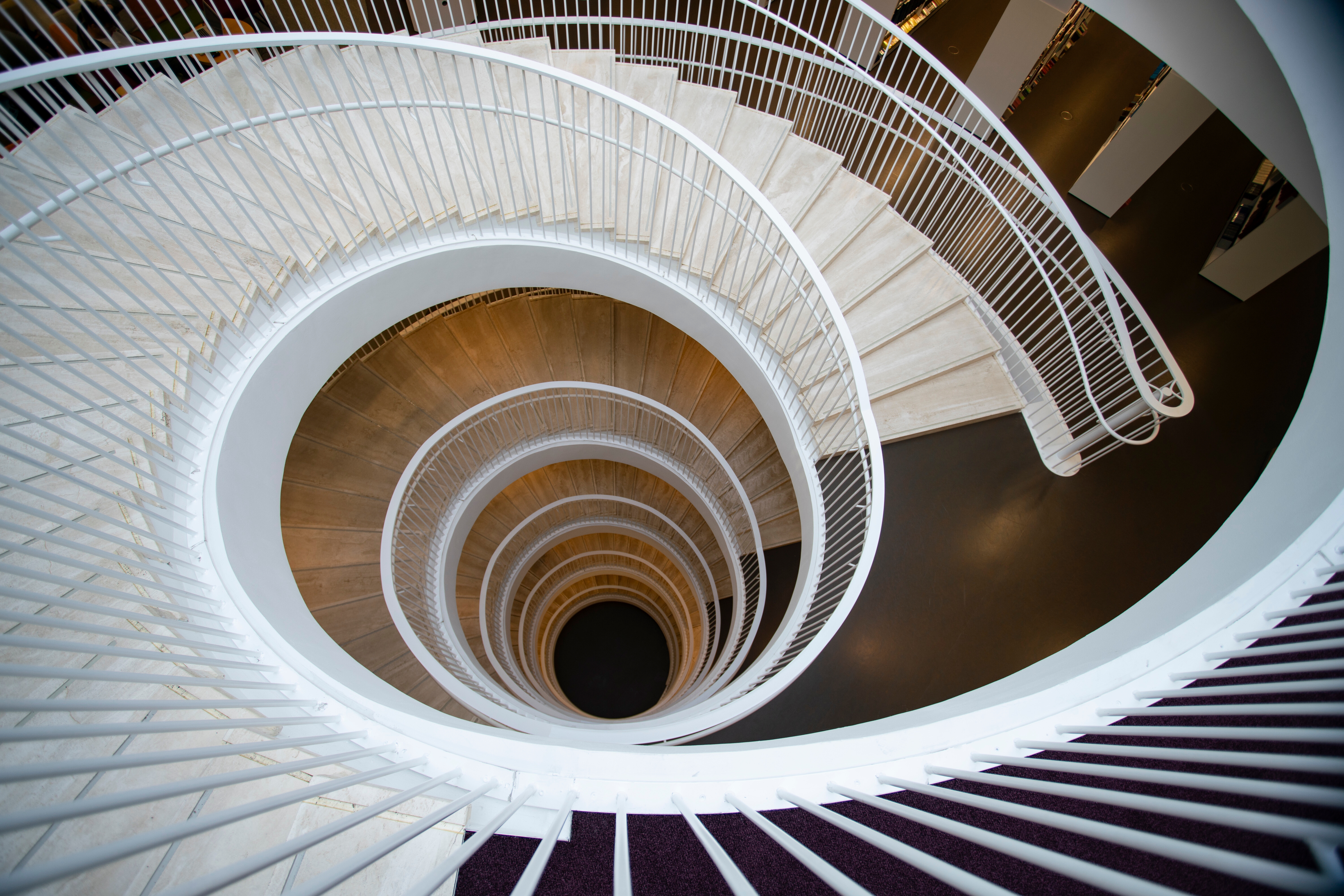 Spiral staircase in a modern building, captured from above, creating a dramatic, swirling visual effect