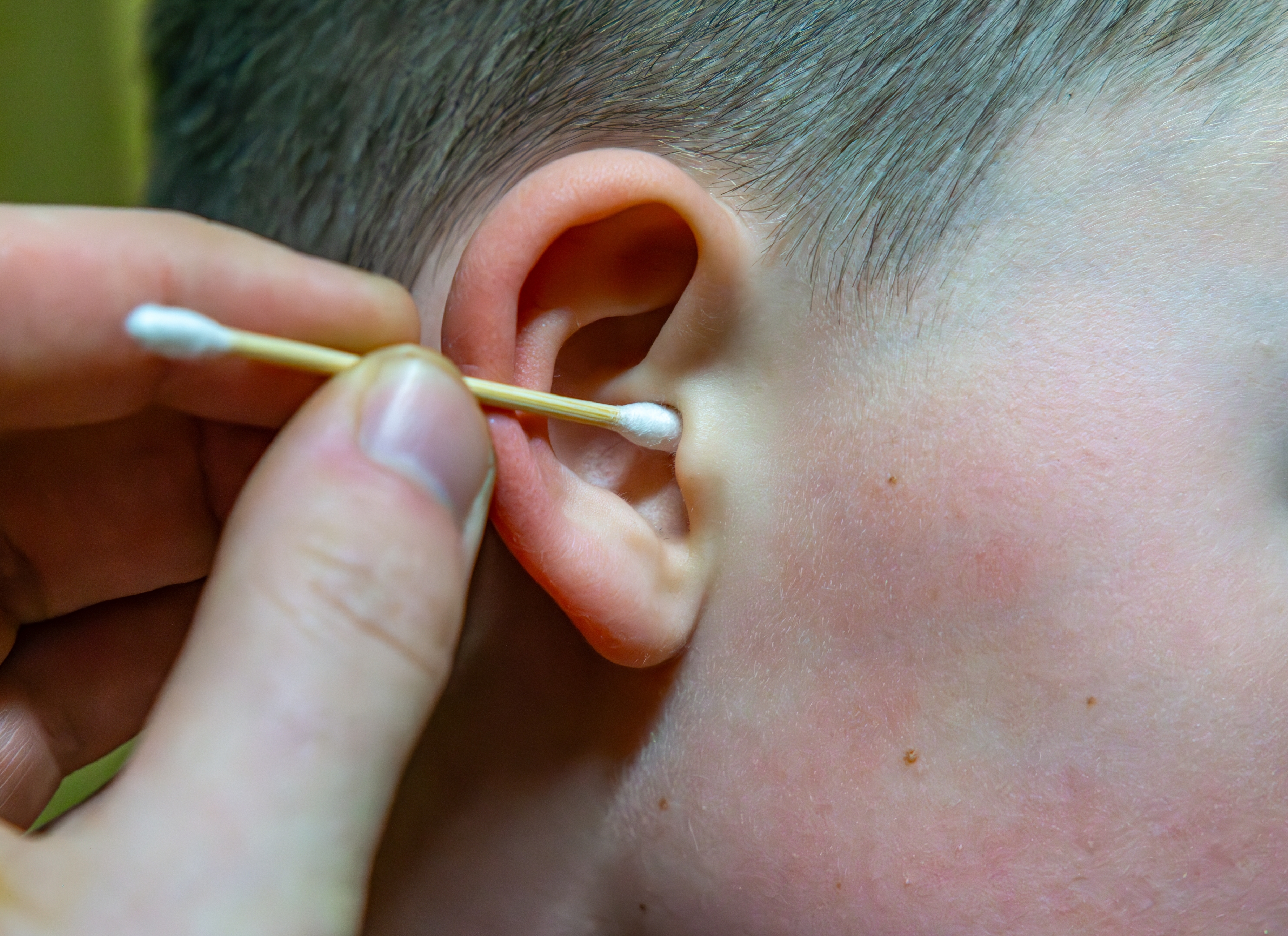 Close-up of a person's ear being cleaned with a cotton swab