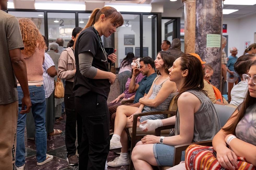 McKay talking to a mom with a burned hand in a crowded waiting room in a scene from "The Pitt"