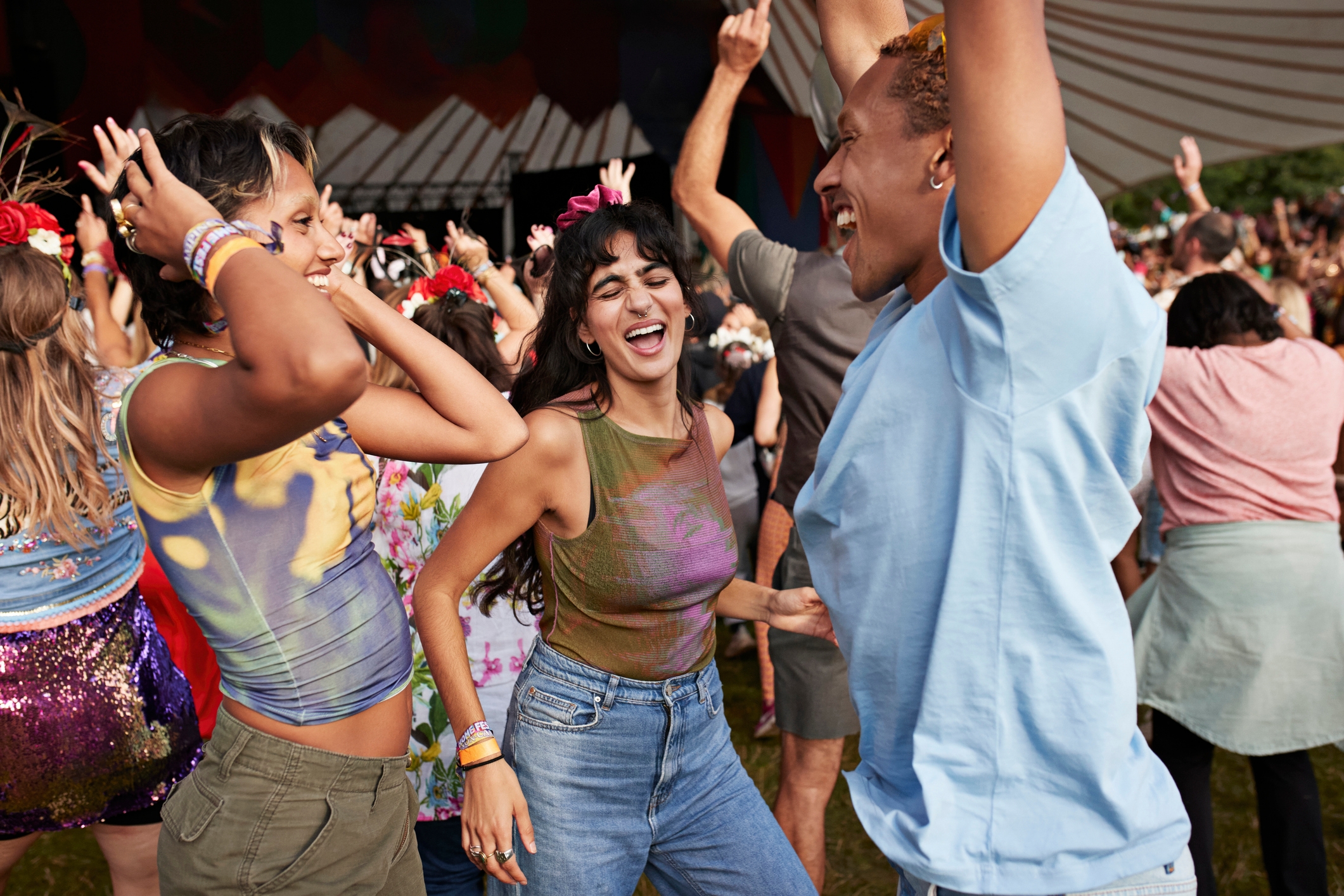 People happily dancing at an outdoor music festival, enjoying the lively atmosphere