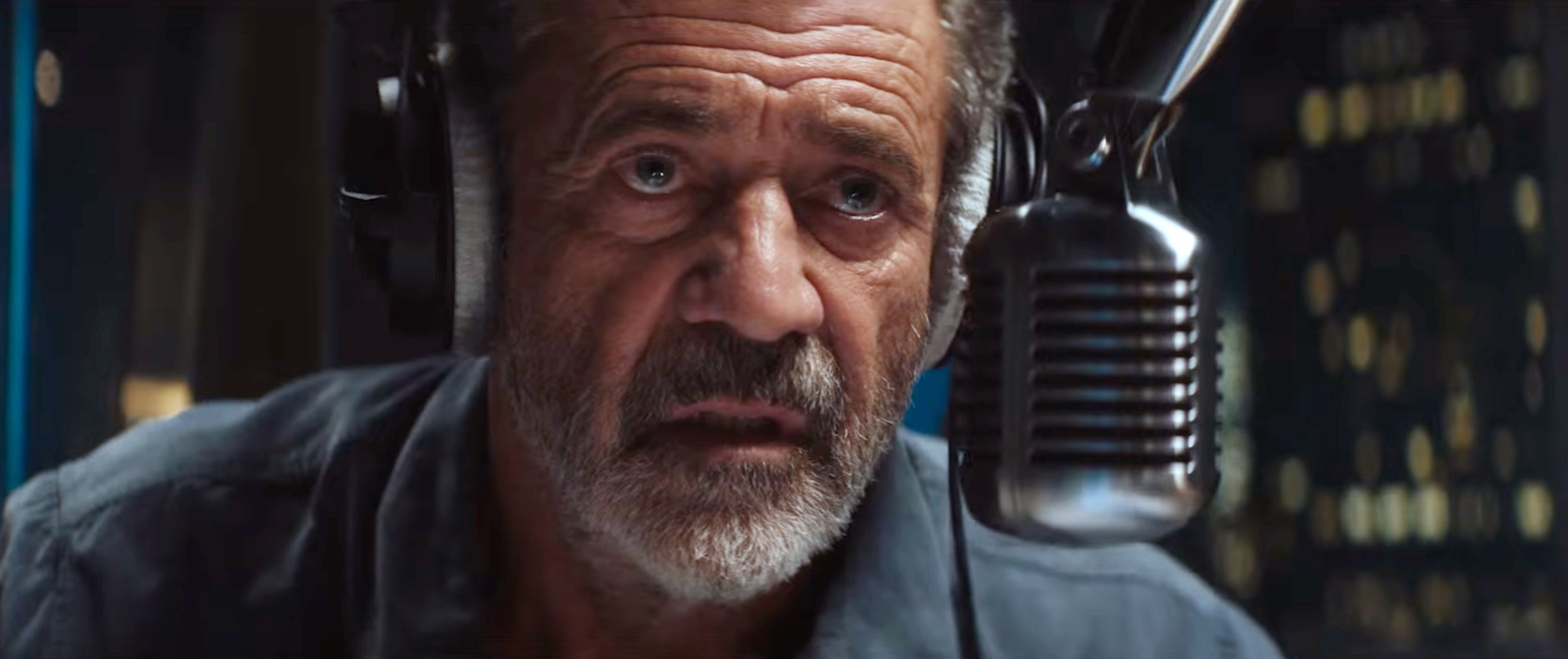 Man wearing headphones speaks into a microphone in a recording studio