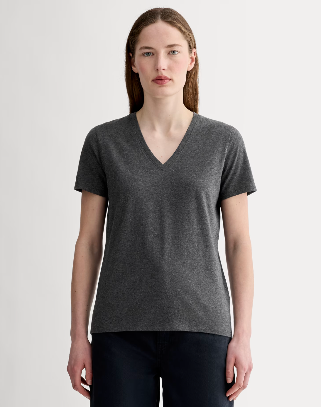 Person wearing a plain V-neck T-shirt, standing against a neutral background