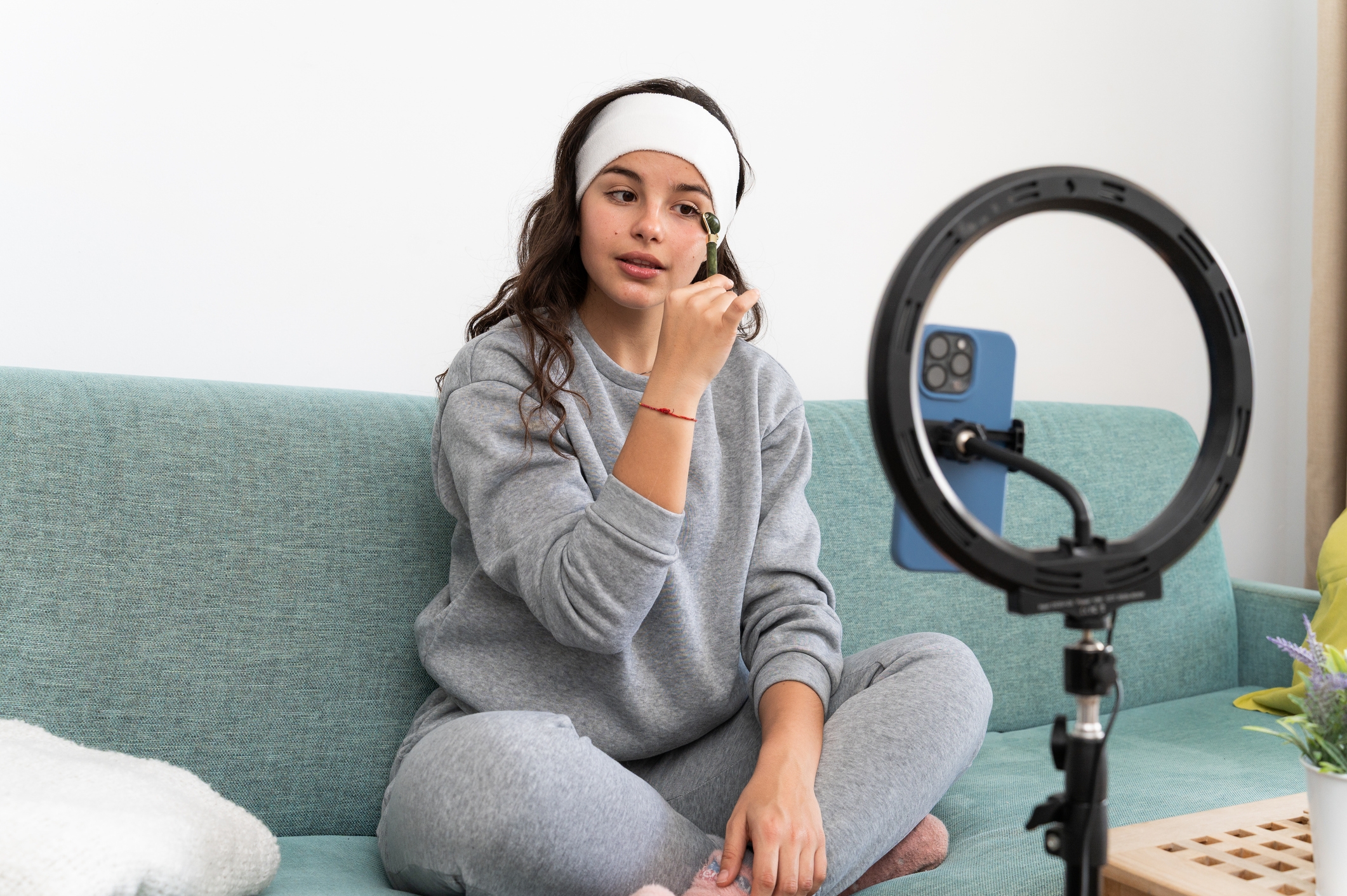 Person in comfortable clothing applies makeup in front of a smartphone and ring light