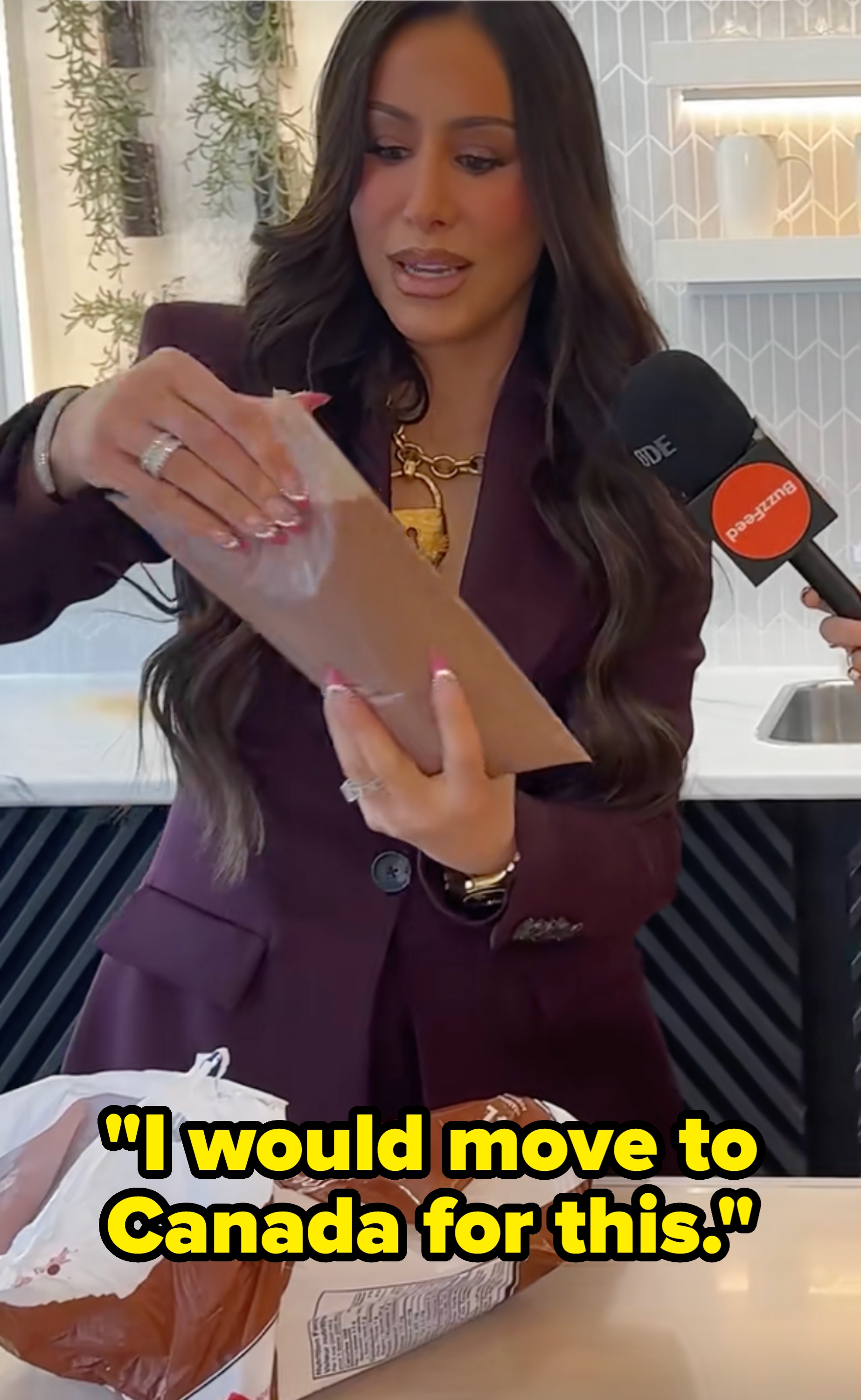 Person in a stylish suit holding a chocolate bar while being interviewed with a microphone