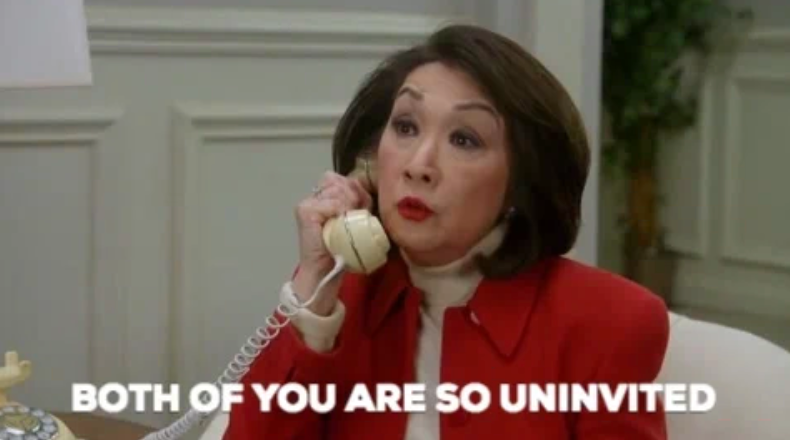 Person holding a phone, wearing a stylish red blazer and white turtleneck, saying "Both of you are so uninvited."
