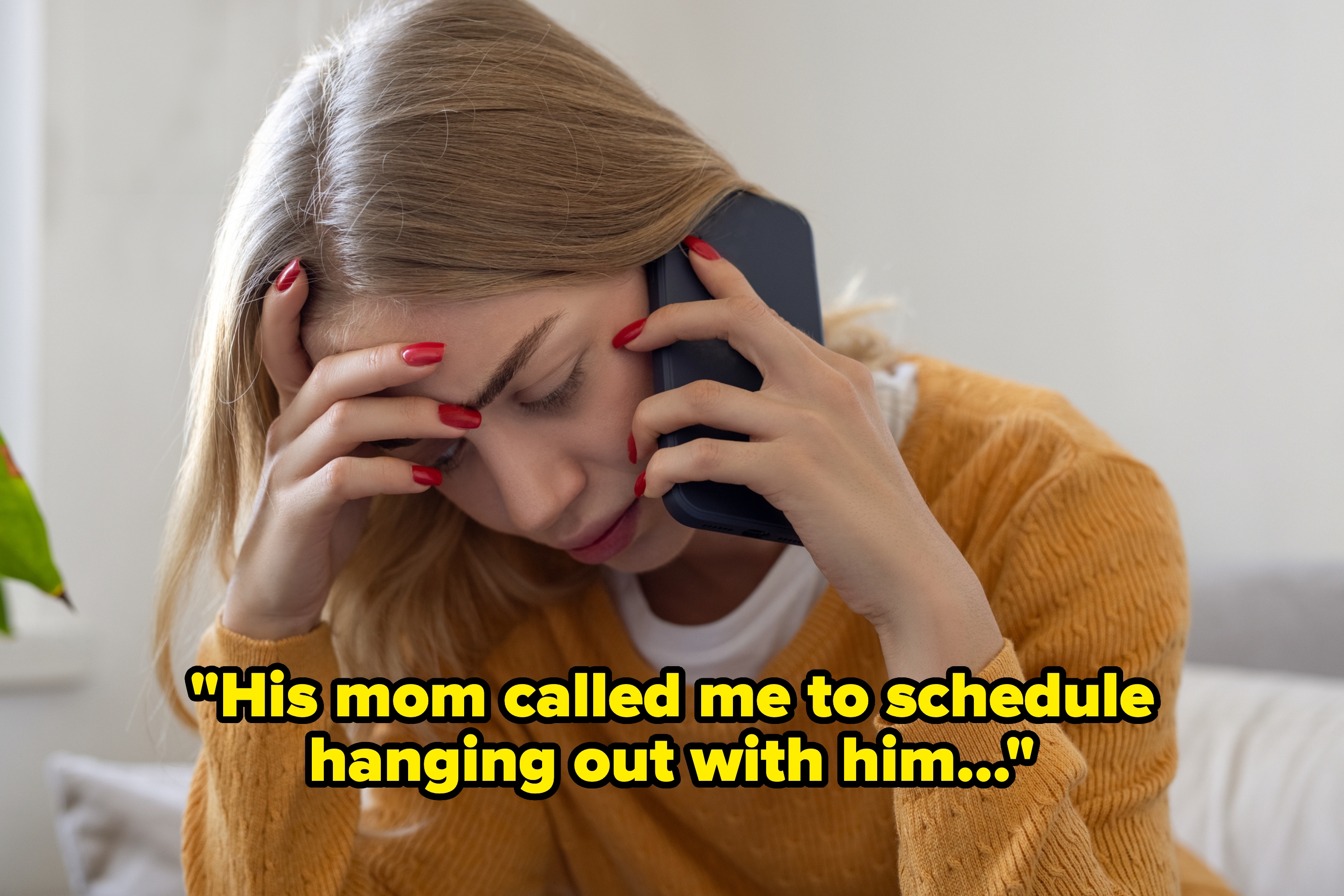 Person on the phone, looking stressed with hand on forehead, wearing a casual sweater, indoors