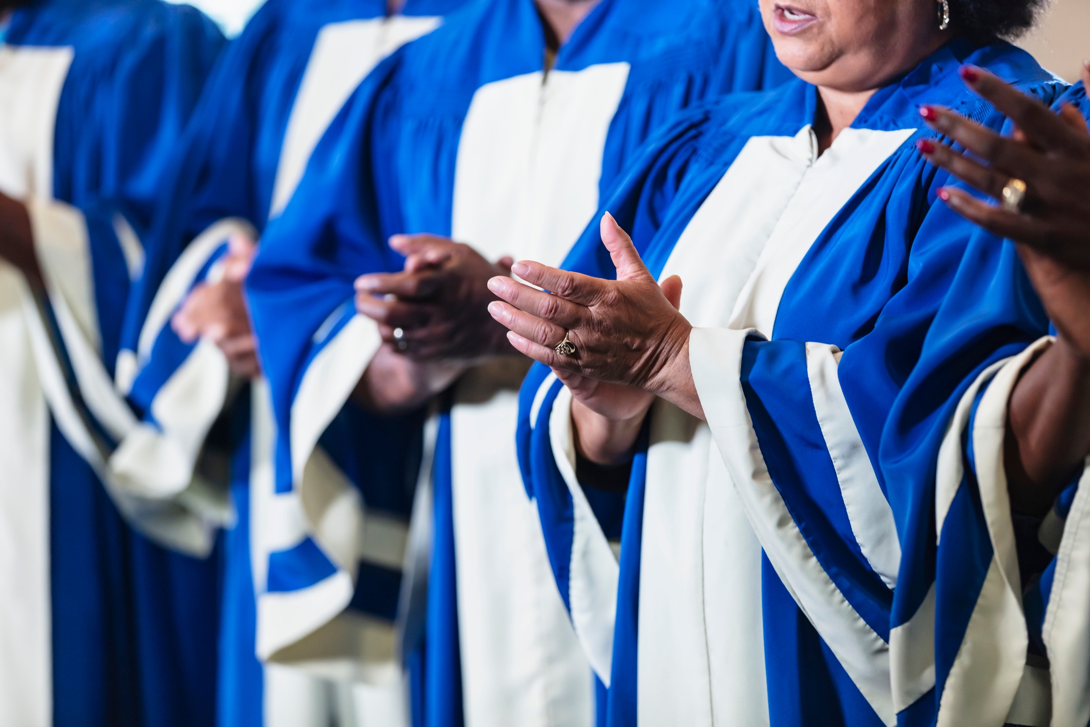 People dressed in blue and white choir robes clapping their hands
