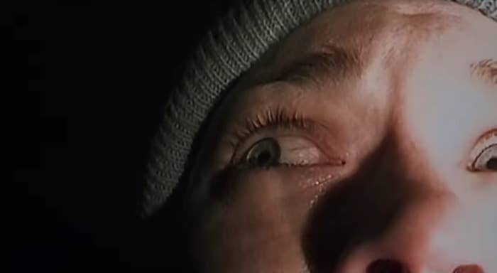 Close-up of a frightened person looking upward, wide-eyed, partially shadowed