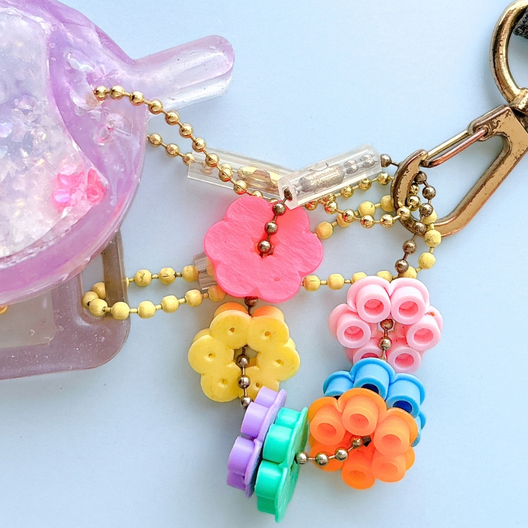 花の形をしたビーズでできたカラフルなキーホルダー。背景に透明のポーチがある。