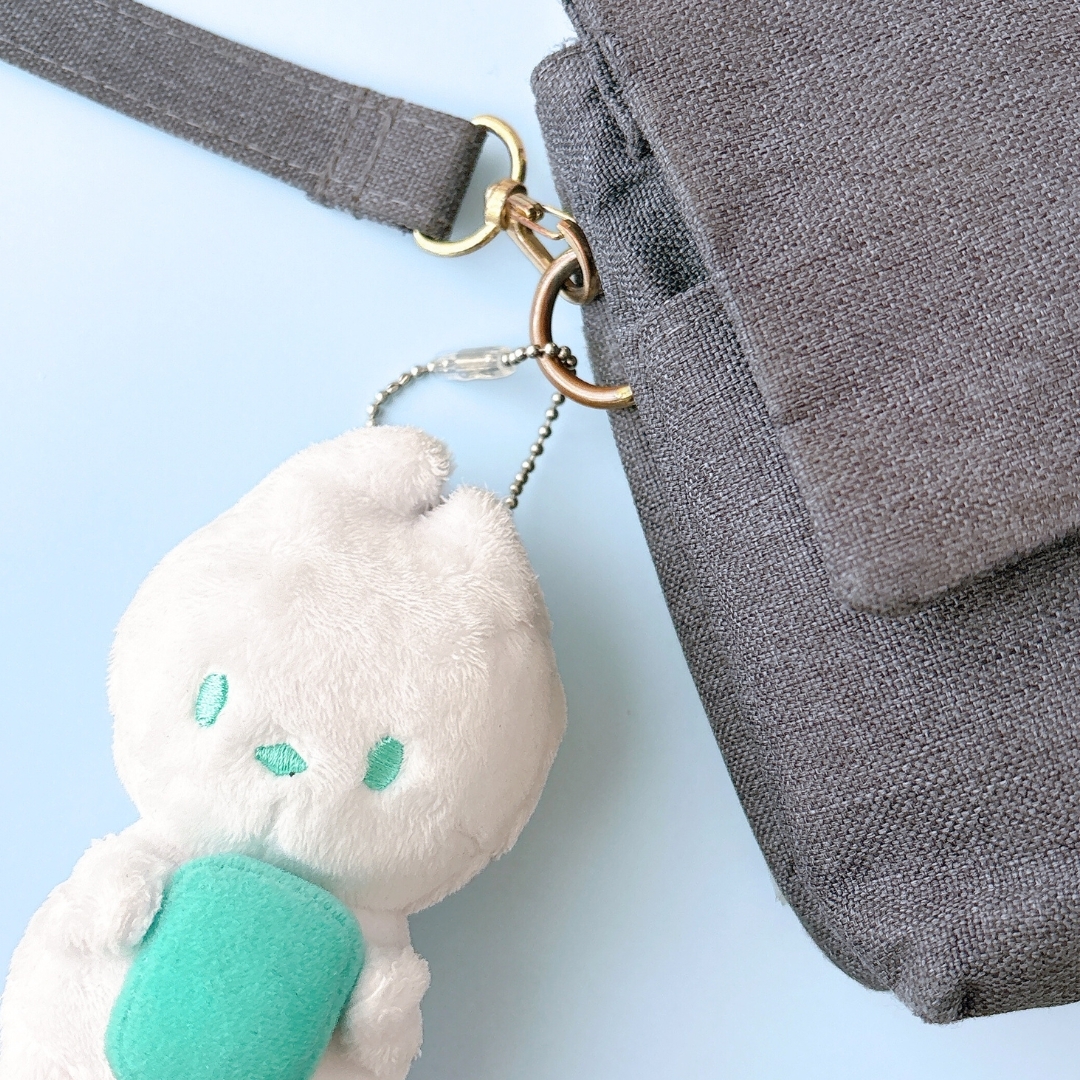 バッグに取り付けられた、かわいい顔のぬいぐるみキーホルダー。