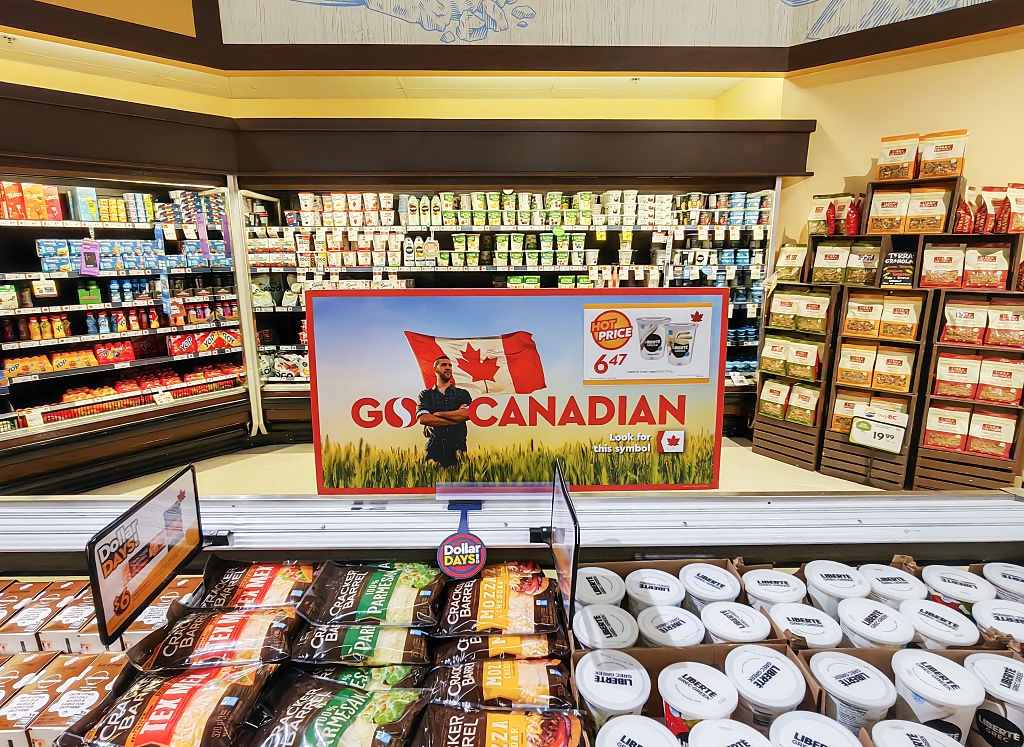 Grocery store aisle with a "Go Canadian" sign featuring Canadian flags and various food products on shelves