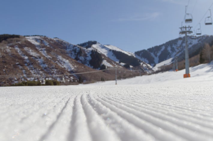 雪山の麓にある整備されたスキーコース。リフトが見え、背景には木の生えた山々が広がる。