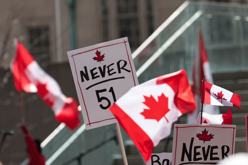 People holding Canadian flags and signs, including one reading "Never 51," possibly indicating a protest or demonstration